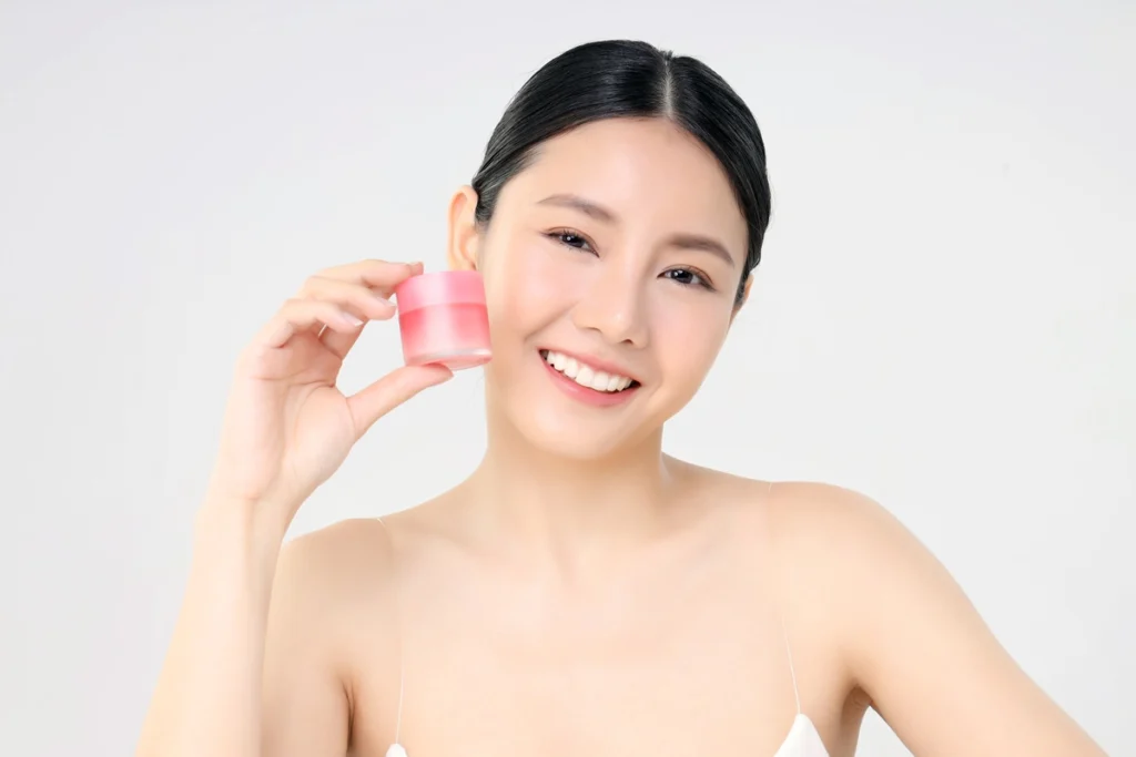 cosmetic facial cream close up beauty face asian woman with fresh clean skin holding facial cream bottle isolated white beauty skin care